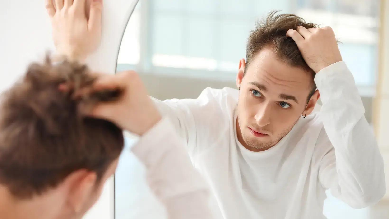 Man looking in mirror with hair loss