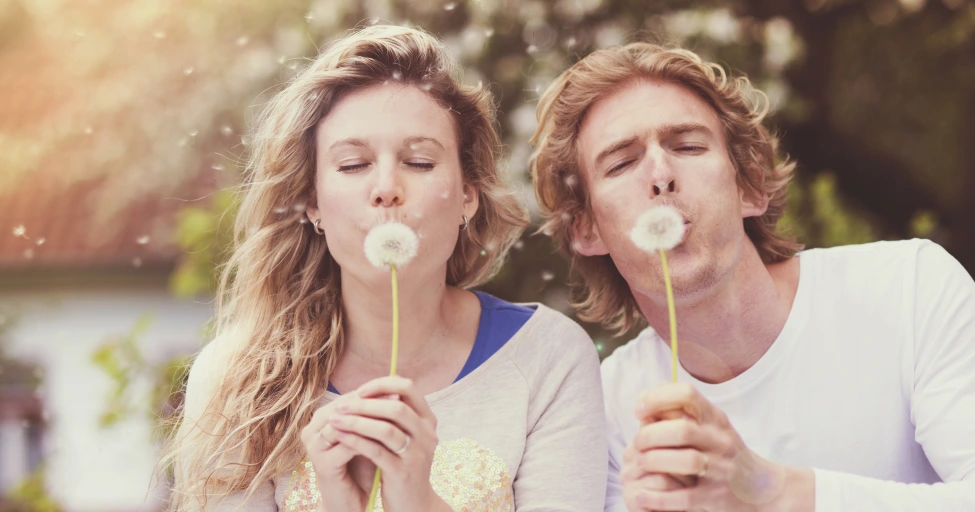Spring skincare, two people enjoying blowing dandelions in the spring